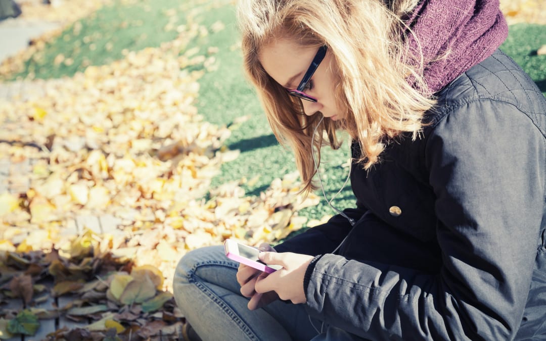 foto del blog di un'adolescente seduta sull'erba che usa lo smartphone a testa in giù