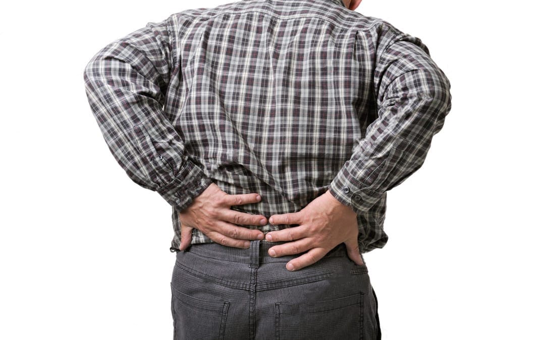 foto del blog di un uomo in piedi che si afferra la parte bassa della schiena dolorante