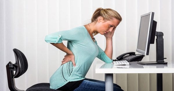 blog picture of lady at desk slumped over grabbing her lower back