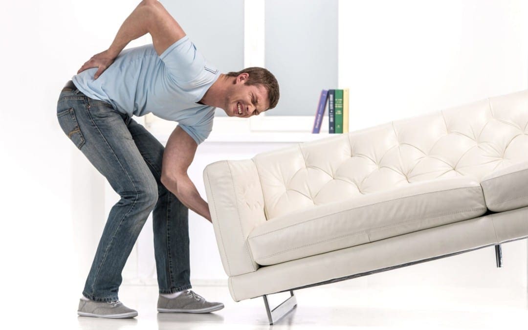 l'uomo che cerca di sollevare il divano nel modo sbagliato ha mal di schiena